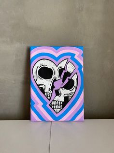 a painting of two skulls in the shape of a heart on a gray wall with blue and pink stripes