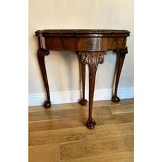 a wooden table sitting on top of a hard wood floor next to a white wall