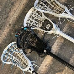 two lacrosse sticks, one black and the other white are laying on top of each other