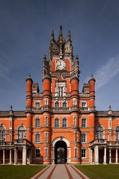 an orange brick building with a clock on the top of it's tower and walkway