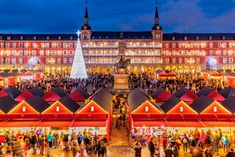 an aerial view of the christmas market in front of a large building with many people walking around it