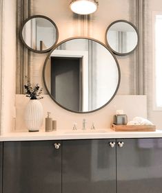 a bathroom vanity with three round mirrors above it