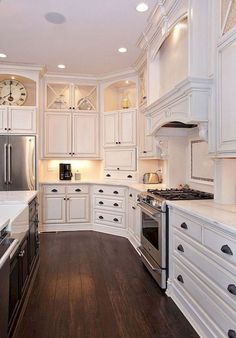 a large kitchen with white cabinets and wood flooring, along with an island in the middle