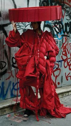 a woman in red is holding an umbrella over her head