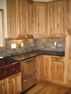 a kitchen with wooden cabinets and black counter tops, wood floors, and stainless steel dishwasher