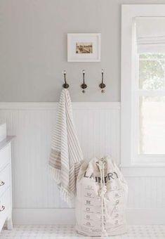 a white and gray bathroom with two towels hanging on the wall next to a window