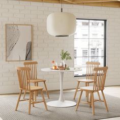 a white table and four chairs in a room with brick walls, windows, and rugs