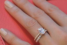 a woman's hand with a diamond ring on top of her finger and an engagement band