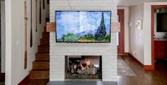 a television mounted on the wall above a fire place in a living room with hardwood floors