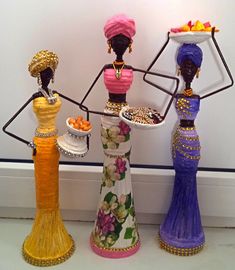 three different colored vases holding plates with food on them in front of a white wall