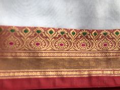 a red and gold sari with green accents on the border is seen in this close up photo