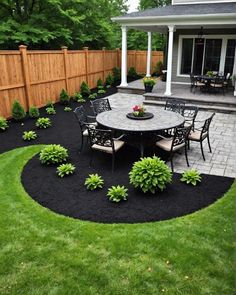 an outdoor patio and dining area with black mulch on the ground, surrounded by green grass