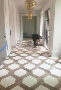 a man is working on the floor in an empty room with white and gray tiles