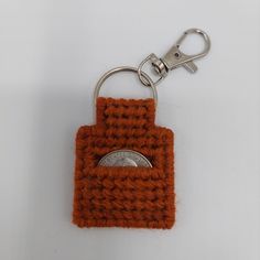 an orange crocheted keychain with a coin in the pocket on it