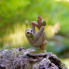 a figurine of a slotty hanging upside down on a tree stump in the woods