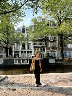 a woman standing on the edge of a brick walkway next to a body of water