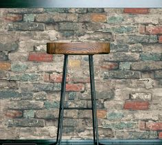 a wooden stool sitting in front of a brick wall with a metal frame on it