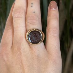 This extremely rare Mid-Century Intaglio ring features an engraved sardonyx set in 10 karat yellow gold. Intaglio rings date as far back as 5000 BC and often depict Neoclassical impressions of warriors and emperors. This cocktail ring features a red sardonyx stone with a deep Vermillion hue. Sardonyx is banded gemstone and variety of chalcedony. This sardonyx features a Roman carving set in a bezel of 10 karat yellow gold. A sister to Cameo jewelry with a scarlet red hue. A right hand ring with Luxury Gold Engraved Ring With Intaglio, Luxury Gold Engraved Intaglio Ring, Heirloom Engraved Ring With Intaglio For Collectors, Formal Carved Signet Ring In 14k Gold, Luxury Intaglio Rings For Collectors, Carved Signet Ring In 14k Gold For Formal Occasions, Carved 14k Gold Signet Ring For Formal Occasions, Heirloom Intaglio Signet Ring For Formal Events, Luxury 14k Gold Signet Ring With Intaglio