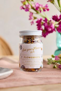 a jar filled with flowers sitting on top of a table next to a knife and fork