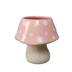 a pink and white mushroom shaped vase with polka dots on the top, sitting on a table