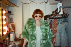 a woman in a green fur coat and sunglasses