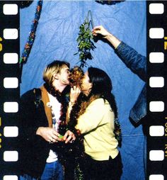 two people standing next to each other in front of a blue background with film strips