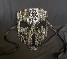 This men's Venetian masquerade mask is made of a lightweight metal and is hand painted. The abstract paint job gives the mask a unique look. Stand out at your next costume or masquerade party with this awesome mask! Mask has some flexibility and come with black silk ribbon ties attached. Mask size 6"W x 7"H. Mask color silver/black. By Essance Masquerade. Metal Mask Masquerade, Venetian Silver Mask For Theater, Venetian Masquerade Masks, Men's Vintage Style, Venetian Masquerade, Cool Masks, Vintage Mens Fashion, Masquerade Party, Costume Mask