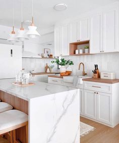 a kitchen with white cabinets and marble counter tops, along with wooden stools in front of the island