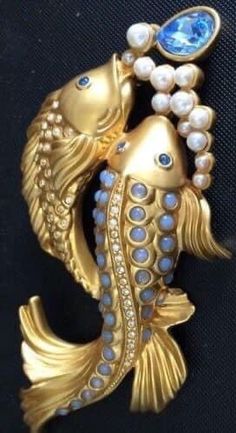 a gold fish brooch with blue stones and pearls