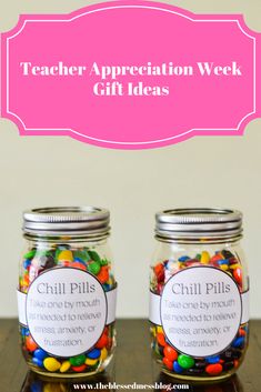 two glass jars filled with colorful candy on top of a wooden table next to a pink sign