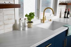 a kitchen sink with two faucets and bottles on the counter top next to it