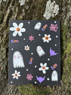 a piece of paper with halloween stickers on it sitting next to a tree trunk