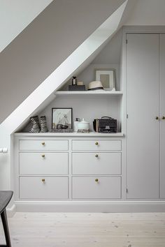 an attic bedroom with white cabinets and drawers