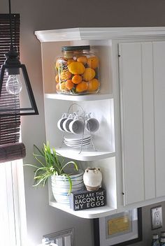 a white shelf filled with jars and oranges