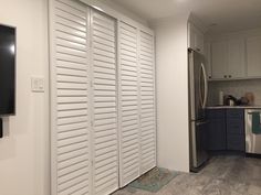 a kitchen with white shutters on the doors and stainless steel appliances in the background