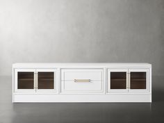 a white entertainment center with glass doors on the front and bottom shelves, against a gray wall