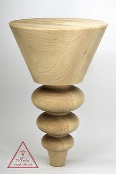 a tall wooden vase sitting on top of a white table next to a red triangle