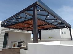 an outdoor covered patio with white walls and wood flooring on the side of it