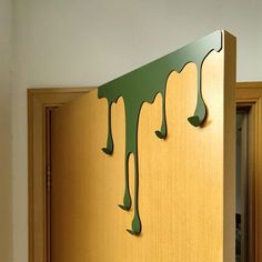 a wooden cabinet with green paint dripping down the front and back side, in a kitchen