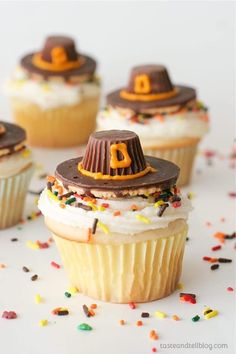 cupcakes decorated with pilgrim hats and sprinkles on a white surface