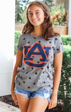 You'll be the "star" of the tailgate in our Auburn Superstar tee! This unique tee features the Auburn logo with a background of black stars on a grey tee. It's the perfect top to wear on gameday or just walking around campus! Pair it with ripped jeans or denim shorts, and your favorite pair of sneakers for a perfect look! Details: *OFFICIALLY LICENSED* Crew Neckline Short Sleeve Relaxed Fit Color: Heather Grey with Black Stars Fabrication: 50% polyester, 38% Cotton, 12% Rayon Anabella is wearing Auburn Logo, Black Stars, Sarasota Florida, Auburn Tigers, Grey Tee, Southern Style, Trendy Clothes For Women, Black Star, Sarasota