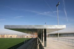 an empty soccer field with grass and blue sky in the background, as well as a large metal structure