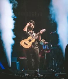 a man holding a guitar while standing on stage