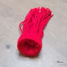 a red piece of yarn sitting on top of a wooden floor