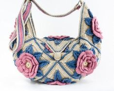 a crocheted purse with pink and blue flowers on the front, sitting on a white surface