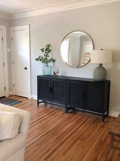 a living room filled with furniture and a large round mirror on the wall above it