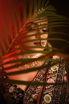 a woman wearing an elaborate dress and holding a palm leaf in her hand, with the light shining on her face