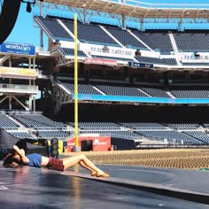 a woman laying on the ground in front of an empty stadium