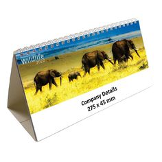 a desk calendar with elephants walking in the grass