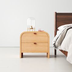 a bed with a wooden headboard and night stand next to it on a white floor